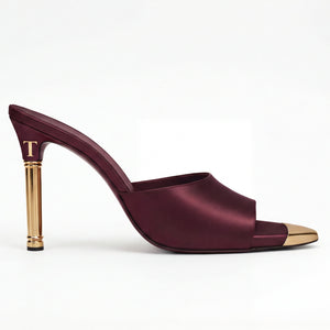 Maroon high-heeled shoe with gold heel on a white background
