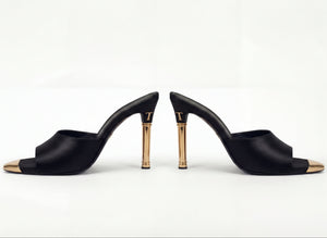 Black high-heeled shoes with gold accents on a white background