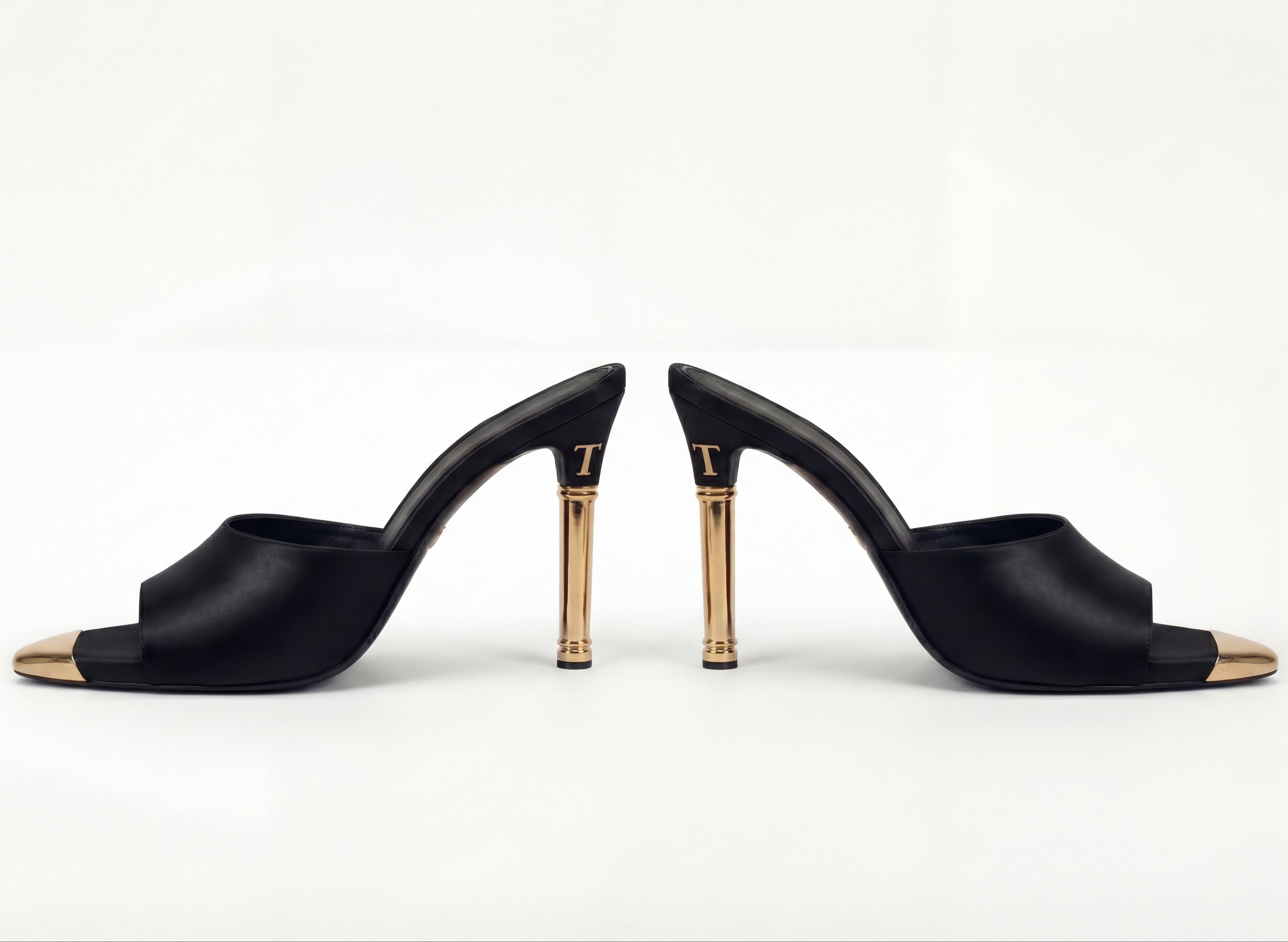 Black high-heeled shoes with gold accents on a white background