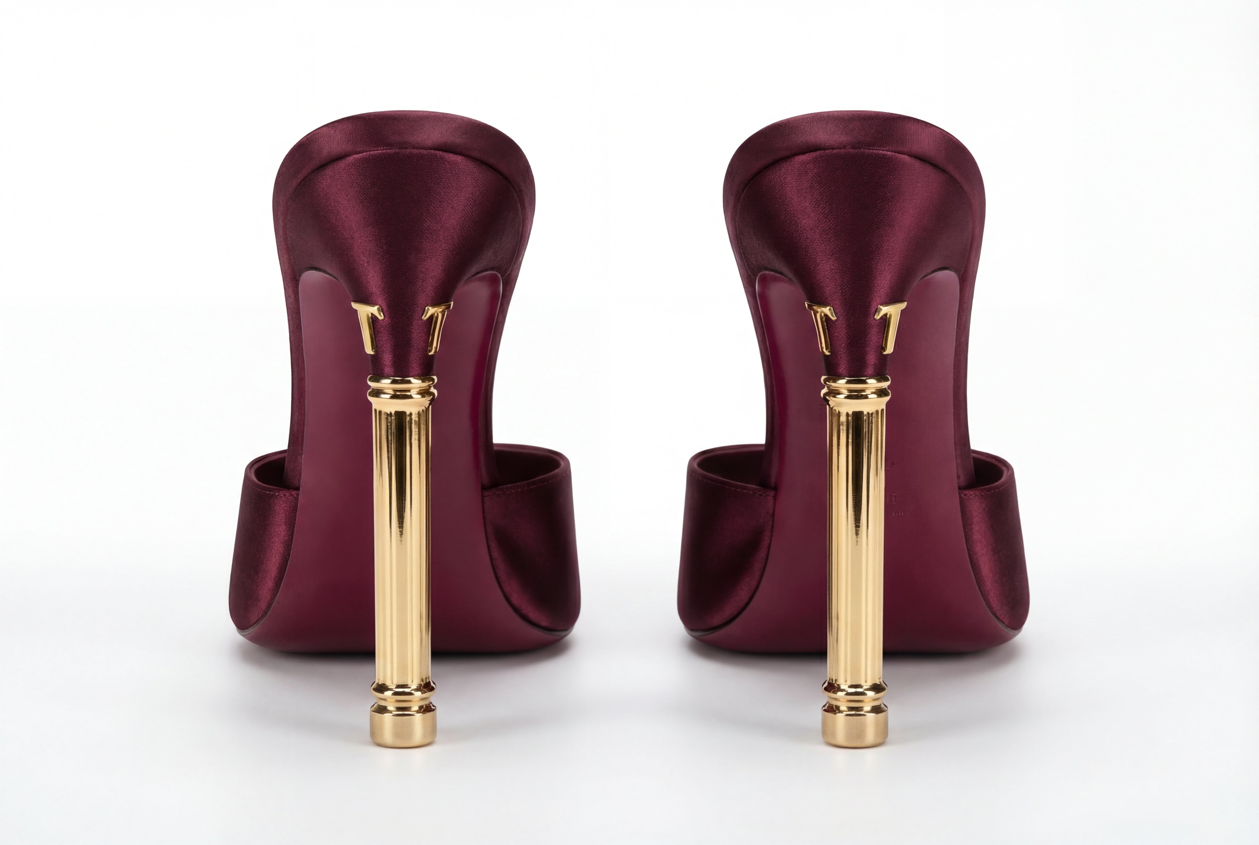 Pair of maroon high-heeled shoes with gold heels on a white background