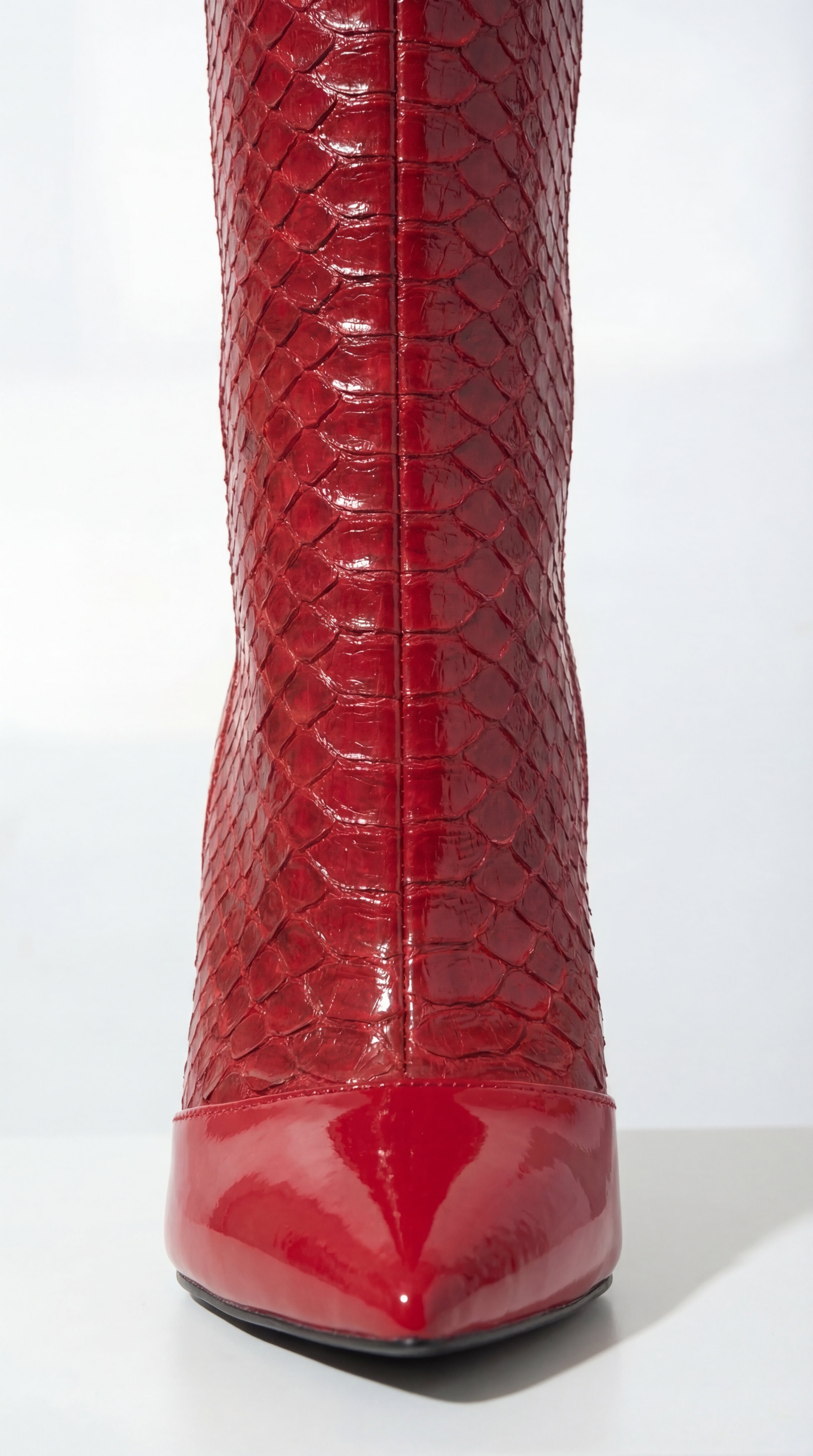 Red patent leather boot with snake skin pattern on a white background