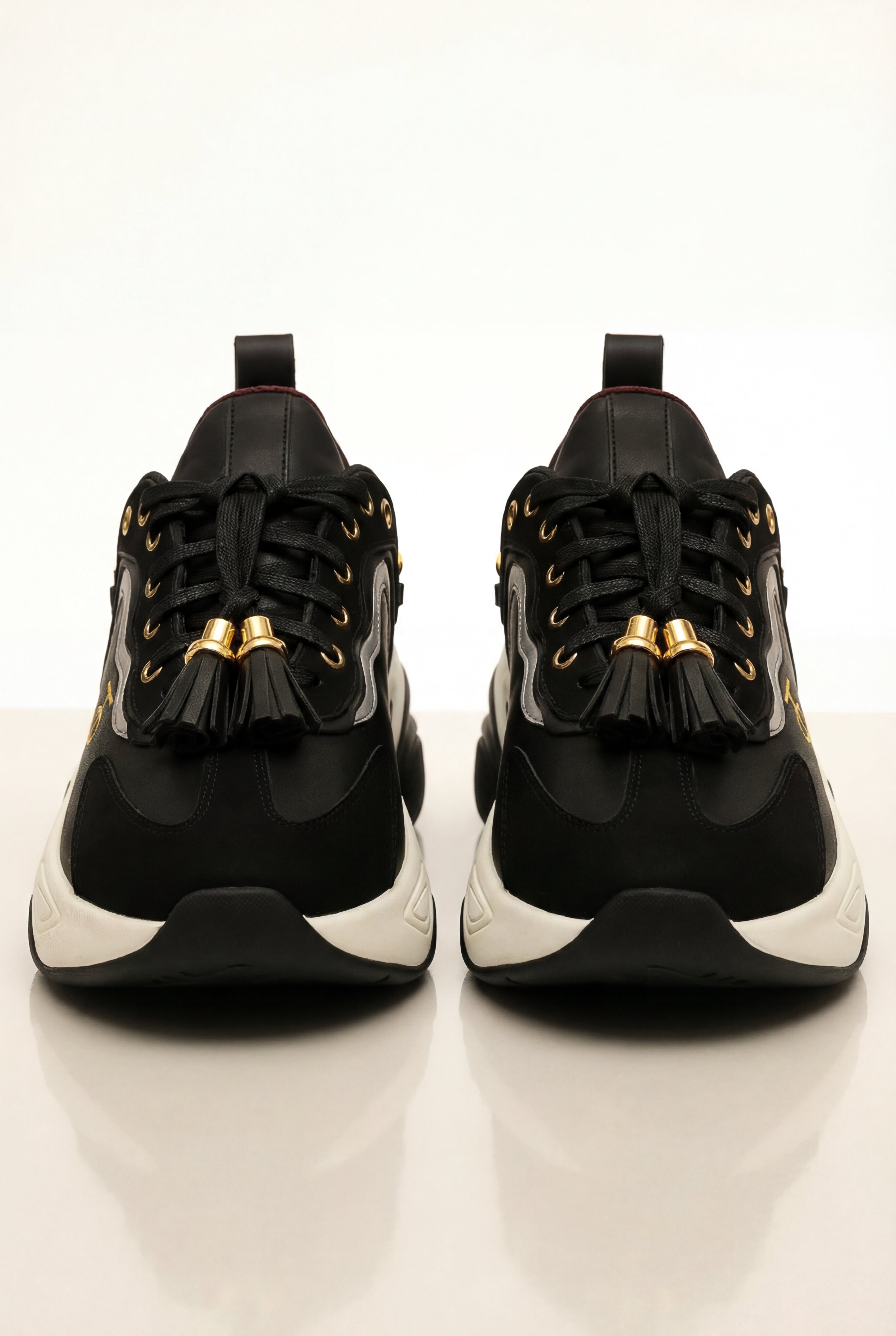 Black sneakers with gold accents on a white background